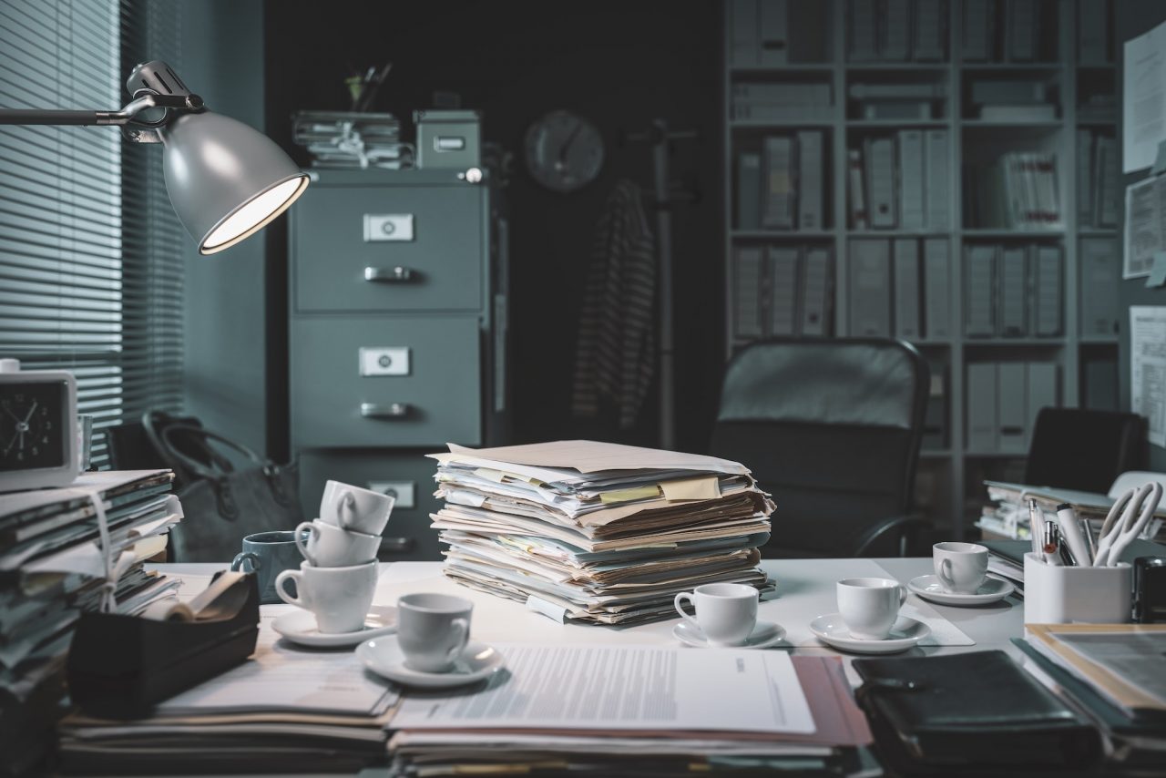 pile of paperwork and coffee cups on the office desk